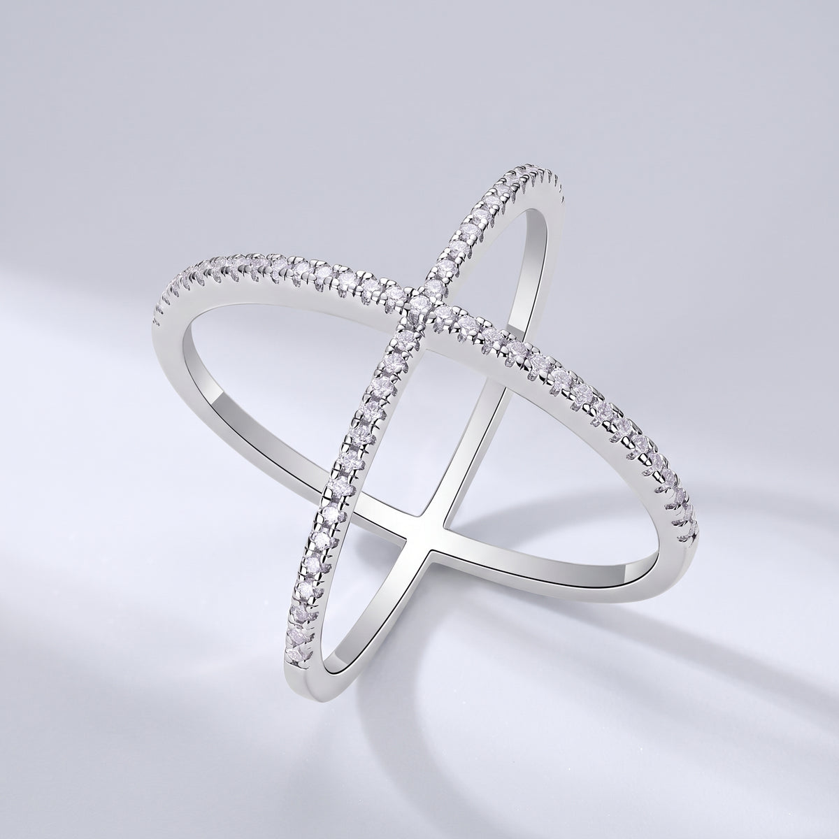 Vellmonto Axis silver crossover ring with moissanite-set bands on a light gray background.