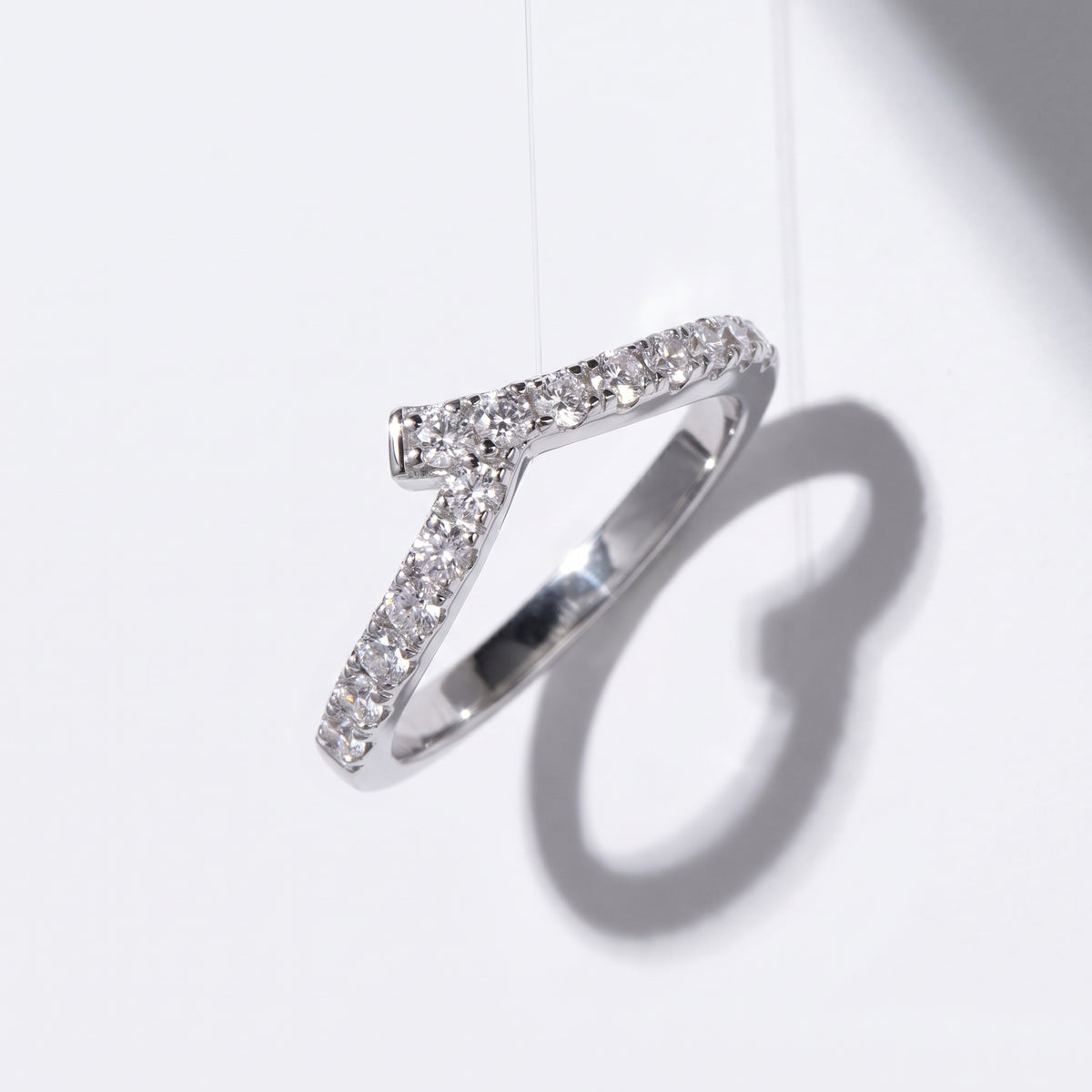 Vellmonto Rush silver moissanite chevron ring casting a curved shadow on a white background.